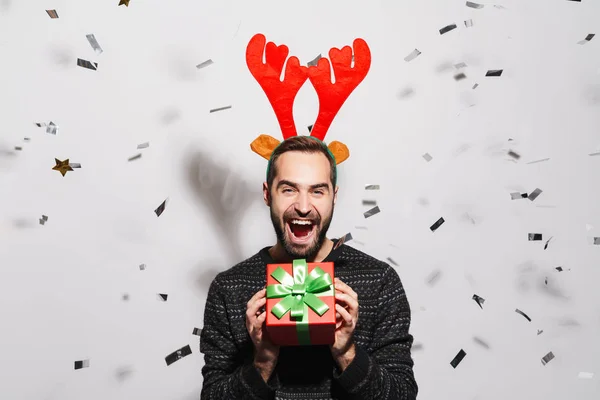 Image of man in reindeer antlers headband holding New Year prese — 스톡 사진