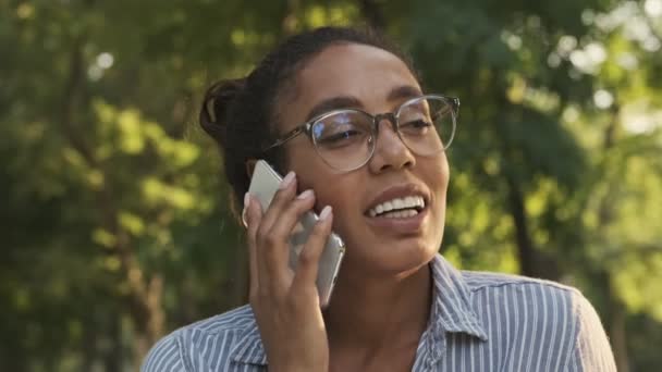 Vrolijk Mooi Afrikaans Vrouw Bril Praten Met Smartphone Terwijl Zitten — Stockvideo