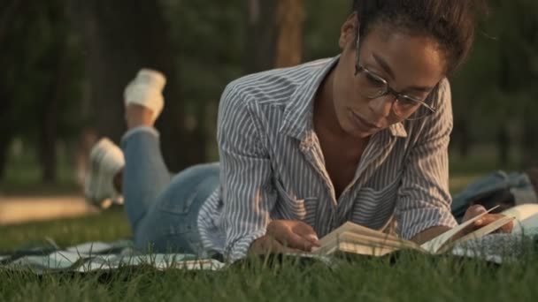 Concentrada Mulher Muito Africana Óculos Lendo Livro Enquanto Deitado Xadrez — Vídeo de Stock