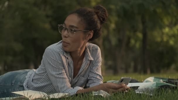 Sonriente Mujer Africana Bonita Pensativa Gafas Con Teléfono Inteligente Mirando — Vídeo de stock