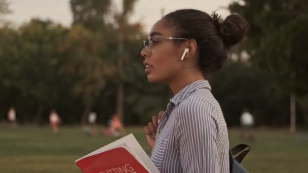 Souriant Jolie Femme Africaine Lunettes Écouteurs Tournant Regardant Autour Dans — Video