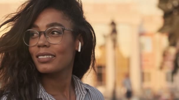 Close Widok Uśmiechnięta Ładna Afrykańska Kobieta Okularach Słuchawkach Obracając Wychodząc — Wideo stockowe