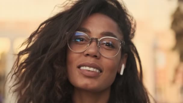 Vista Cerca Sonriente Mujer Africana Con Gafas Auriculares Escuchando Música — Vídeo de stock