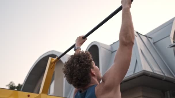 Focused Young Curly Man Doing Sports Exercise Horizontal Bar Outdoors — 비디오