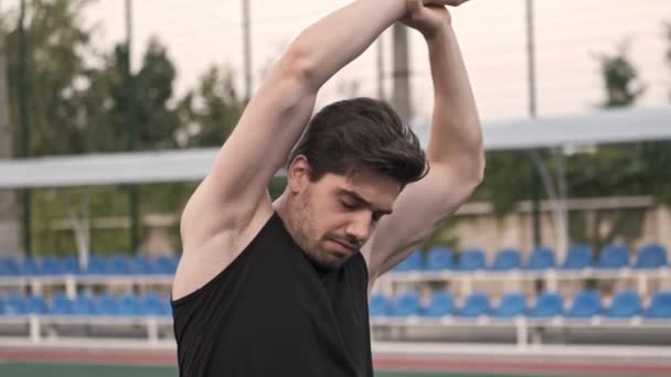 Poważny Przystojniak Rozciągający Się Rękami Patrzący Stadion Świeżym Powietrzu — Wideo stockowe