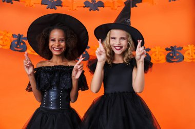 Image of joyful multinational girls smiling with fingers crossed