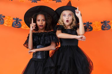 Image of surprised multinational girls pointing fingers upward