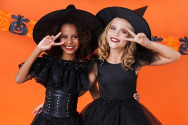 Image of lovely witch girls smiling and gesturing peace sign