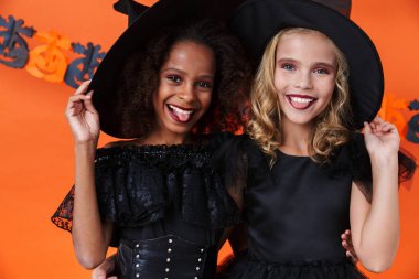 Image of amusing witch girls smiling and hugging together