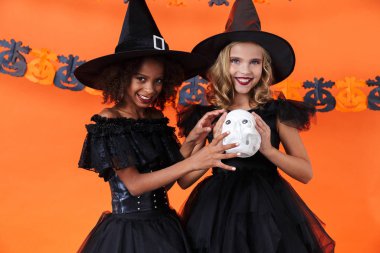 Image of joyful multinational girls holding toy skull and smiling