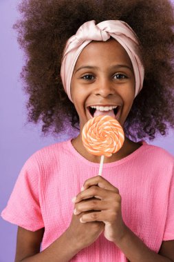 Neşeli, iyimser, Afrikalı genç kız lolipop yiyor..