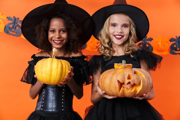 Image of joyful multinational girls holding pumpkins and smiling — 스톡 사진