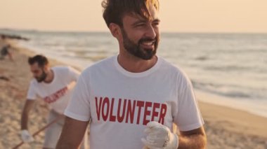 Mutlu çevreci gönüllüler plajları plastikten deniz kıyısında tırmıklarla temizliyorlar.