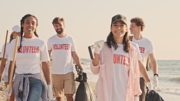 积极快乐的笑着生态志愿者们正在海边的袋子里倒垃圾 — 图库视频影像