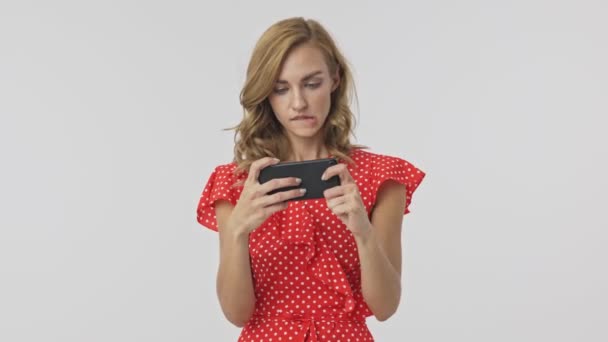 全神贯注的金发美女穿着智能手机 在灰蒙蒙的背景下享受这一刻 — 图库视频影像
