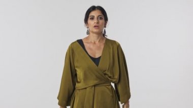 Gri arkaplandan kameraya bakarken kollarında jestlerle çığlık atan geleneksel giysili kızgın Hintli kadın.