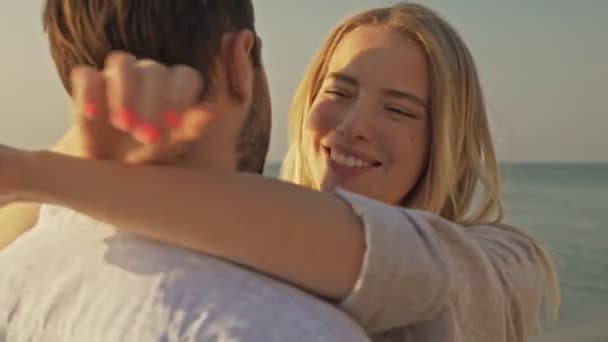 素敵な若いカップルの男と女はビーチでお互いを抱き合っている — ストック動画