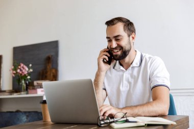 Handsome young bearded man sitting at the table at home