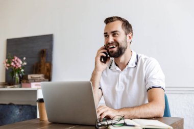 Handsome young bearded man sitting at the table at home