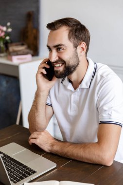Handsome young bearded man sitting at the table at home
