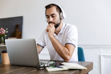 Handsome young bearded man sitting at the table at home