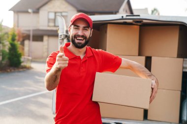 Paket kutusunu tutan ve kamerayı işaret eden teslimatçı resmi