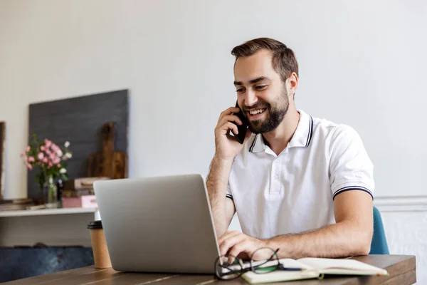 Stilig ung skäggig man som sitter vid bordet hemma — Stockfoto