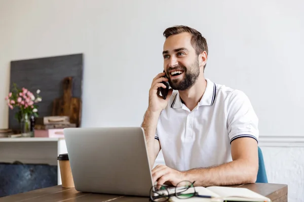 Stilig ung skäggig man som sitter vid bordet hemma — Stockfoto