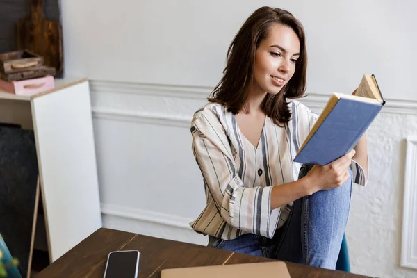 Schönes lächelndes junges Mädchen sitzt zu Hause am Tisch — Stockfoto