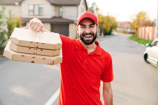 Bild eines fröhlichen jungen Zustellers, der Pizzakartons in der Hand hält und lächelt — Stockfoto