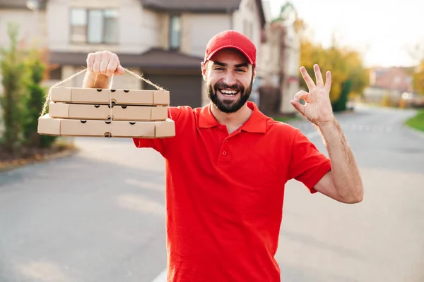 Imagem do homem de entrega alegre segurando caixas de pizza e mostrando sinal ok — Fotografia de Stock