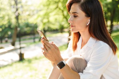 Mutlu ve çekici genç bir kadın bankta dinleniyor.