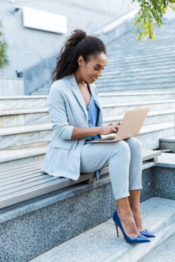 Güzel gülümseyen Afrikalı genç bir iş kadını oturuyor.