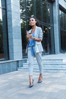 Çekici gülümseyen Afrikalı iş kadını dışarıda yürüyor.