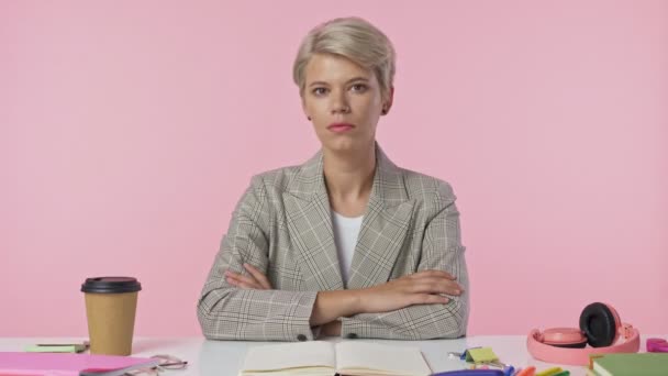 Egy Csinos Fiatal Magabiztos Kijavítja Kabátját Miközben Asztalnál Rózsaszín Háttérrel — Stock videók