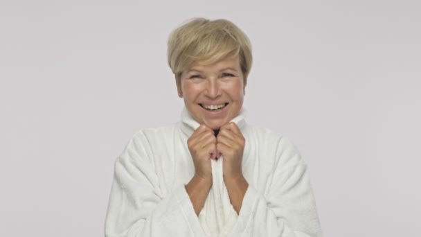 eine fröhliche erwachsene Frau im Bademantel lächelt isoliert über weißem Hintergrund