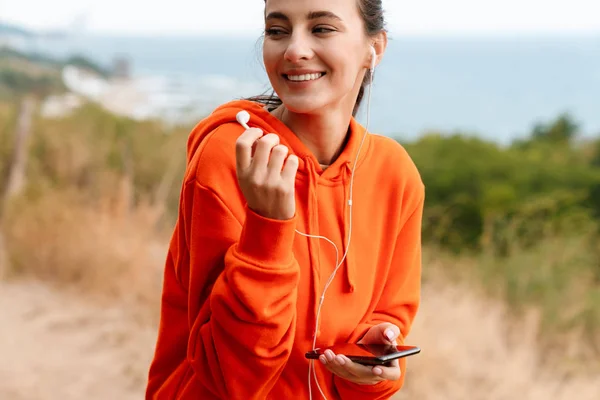 Foto einer freundlich lächelnden Frau mit Kopfhörer und Handy — Stockfoto