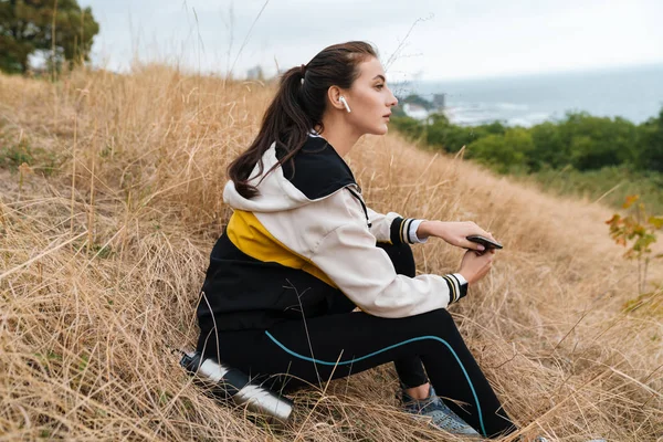 Photo of nice caucasian woman using earpods and smartphone — 스톡 사진