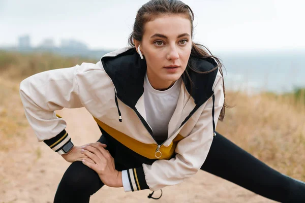 Photo of nice athletic woman using earpods and doing exercise — Stock Photo, Image