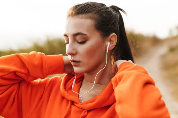 Foto av vacker atletisk kvinna som använder hörlurar medan du tränar — Stockfoto