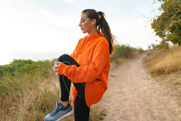 Foto de una hermosa mujer atlética usando auriculares y haciendo ejercicio — Foto de Stock