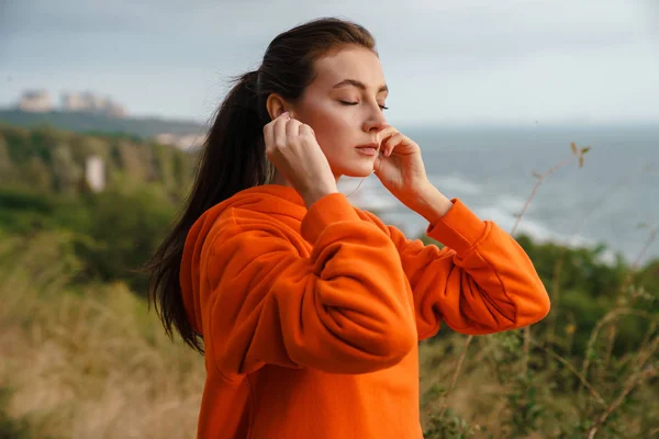 Foto van mooie brunette vrouw met behulp van oortelefoons en het doen van oefening — Stockfoto