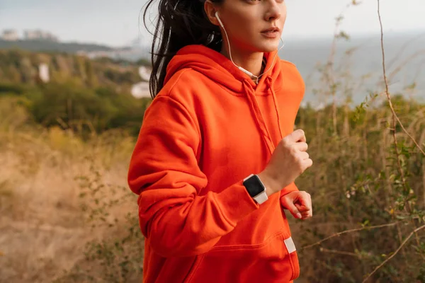 Foto de mujer atlética usando auriculares y smartwatch mientras corre — Foto de Stock