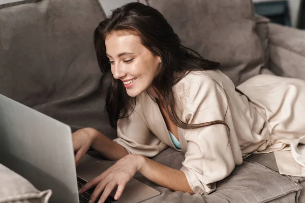 Imagem de jovem mulher bonita usando computador portátil no sofá em — Fotografia de Stock