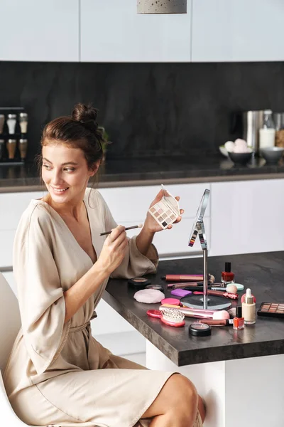 Image of caucasian young beautiful woman applying face makeup at