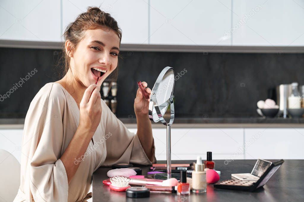 Image of caucasian young beautiful woman applying face makeup at