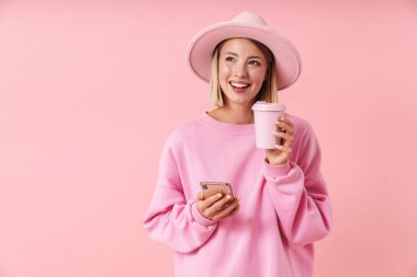 Şapkalı, elinde akıllı telefon ve kahve fincanı olan güzel bir kadının portresi.