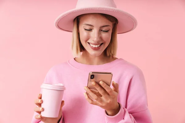 Retrato de mulher otimista em chapéu segurando smartphone e xícara de café — Fotografia de Stock