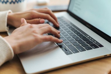Genç beyaz bir kadının laptopta yazı yazarken çekilmiş fotoğrafı.