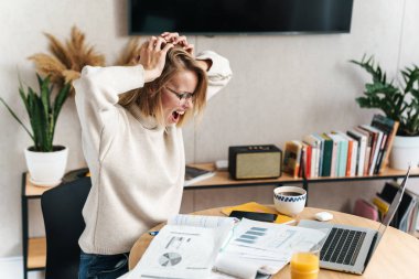 Sinirli bir kadının çığlık attığı ve belgelerle çalıştığı fotoğraf.